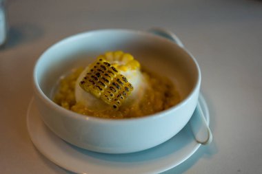 Beyaz kasede kızarmış mısır ve vanilyalı dondurma, seçici bir odak noktası.