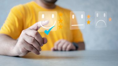 Müşteri hizmetleri ve memnuniyet konsepti. Adam, mutlu gülümseyen yüz ikonunun sanal ekranına dokunur ve hizmette tatmin olur. reyting çok etkileyici.