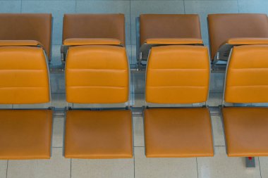 Modern havaalanı terminalinde bekleme salonu, havaalanında turuncu sandalyeler. Tatil görüşü