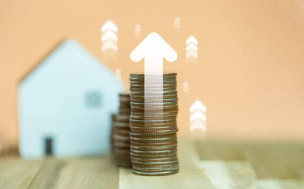 Coins stack for real estate and blur house background and icons of arrow up. Dividend of the house or Increased value of real estate. Earning profit from home. Home loan interest