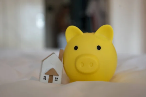A yellow cute piggy bank and home on a bed. Business financial of money savings for real estate concept