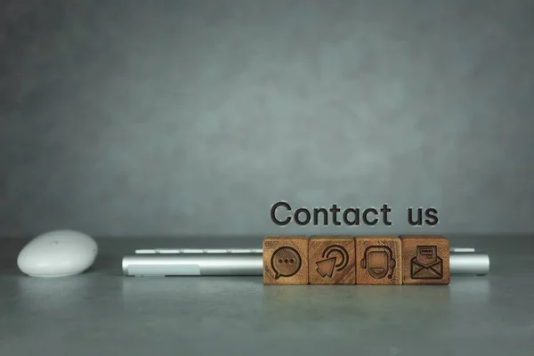 Contact Us symbols on wood blocks with keyboard and mouse. Contact us connection concept with copy space.