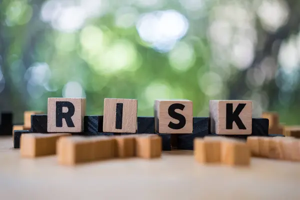 Risk assessment, decision to accept business result in uncertainty, unpredictable situation concept, cube wooden block with alphabet building the word RISK.