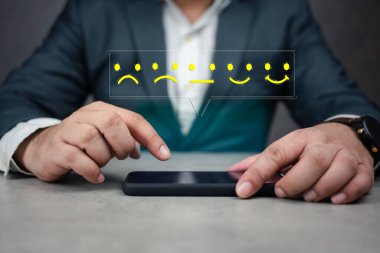 Müşteri konseptini tecrübe eder. Telefon uygulaması üzerinden olumsuzdan olumluya geri bildirim vermek için yüz simgesi. Deneyimini cep telefonundaki bir uygulamayla değerlendiren bir adam..