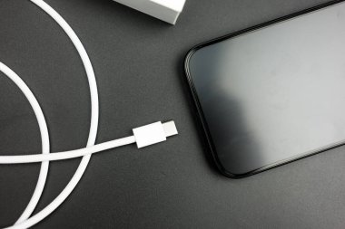 Bangkok, Tayland - 15 Ekim 2023: Usb tip C kablo şarj edici iPhone 15 Pro blue Titanium siyah arka planda