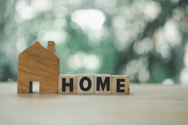 Ahşap ev modeli ve ev sahibinin metni. Yeşil doğa kopyalama alanı olan ev satın almak için tasarruf ve ev bulma kavramsal imajı