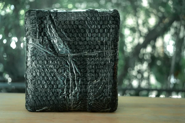 Black bubble wrapped with adhesive tape for packing fragile items. Bubble wrap pliable transparent plastic material used for packing fragile items.