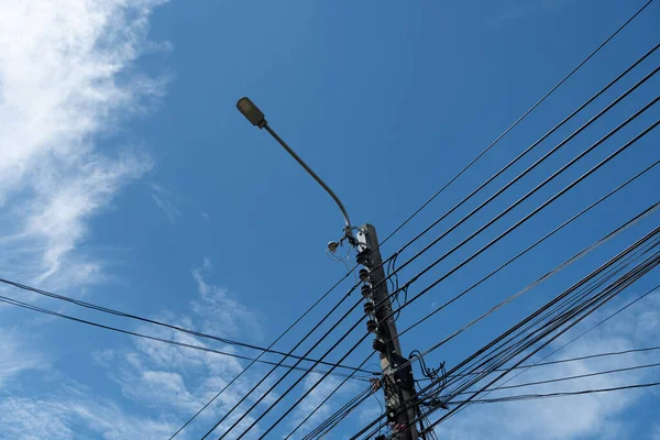 Led street light with a cloudy blue sky. Electric pole power lines and wires