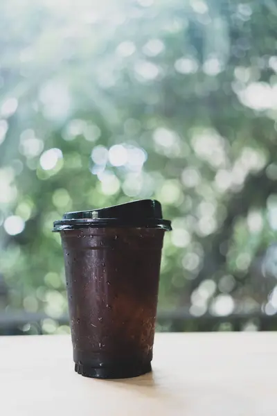 A cup of iced black coffee against nature background