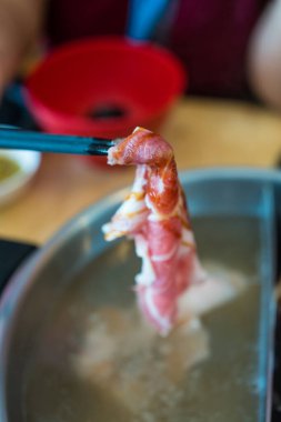 Domuz etini sıcak tencerede çubuk kullanarak tutmak. Kapat.