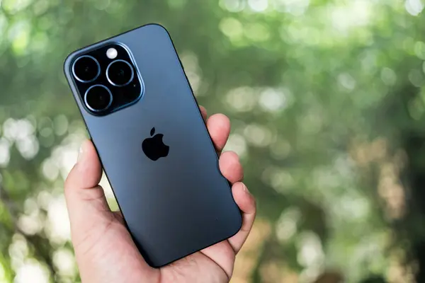 Bangkok, Tayland - 15 Ekim 2023: New Apple iPhone 15 Pro mavi titanyum erkek elinde, bulanık arkaplan, son model akıllı telefon.