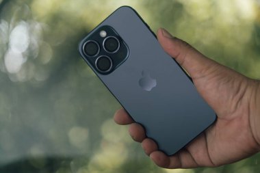 Bangkok, Tayland - 17 Ekim 2023 iPhone 15 Pro Blue Titanium 'u tutan adam. Teknolojik akıllı telefon modern tasarım, 48 megapiksel ana kamera ve Dinamik Ada
