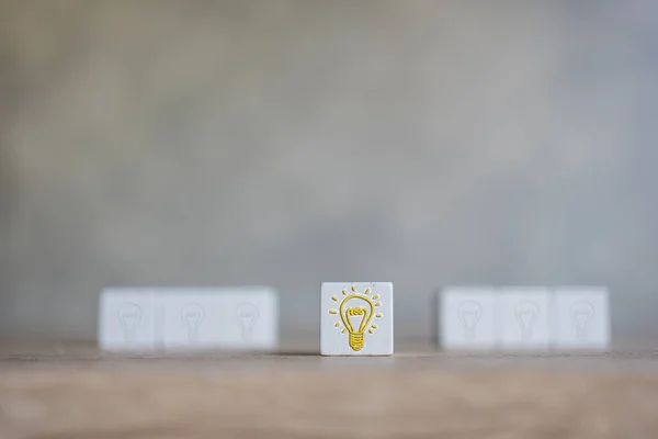 Innovative idea concept. The one of the wooden blocks with a bright light bulb on the center and front of light bulb blur. New initiative and strategy. Creative inspiration