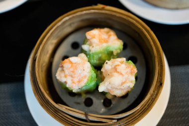 Dim sum 'u kapat, Çin usulü karides buğulanmış hamur köftesi tarifi yeşil wonton ambalajıyla sarılmış.