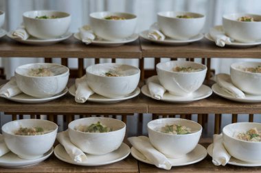 Düğün töreninde konuklar için hazırlanmış beyaz bir kasede kaynamış pirinç çorbası, aperatif yemekler.