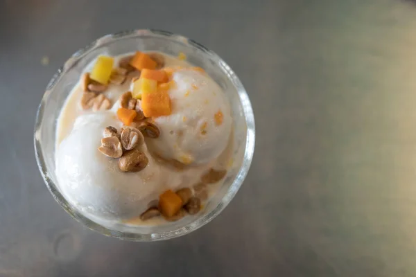Coconut milk ice cream with frozen egg yolk and topping in glass bowl