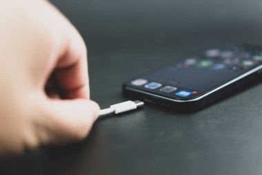 Bangkok, Tayland - 27 Ekim 2023: İnsan tipi kabloyu iPhone 15 Pro mavi Titanyum 'a bağlıyor. C Tipi Şarj Makinesi.