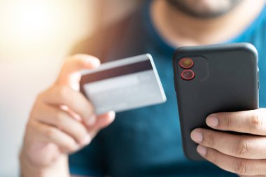 Kredi kartı tutan ve akıllı telefon kullanan bir adam, iş adamı online alışveriş, e-ticaret, internet bankacılığı, harcama