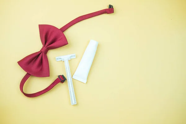 Disposable hotel products, shave cream, recyclable disposable razor and red red bow tie. Top view