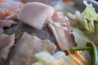 Bir parça çiğ domuz yağı sıcak tavanın ortasına yerleştirildi. Geleneksel Tayland usulü barbekü.