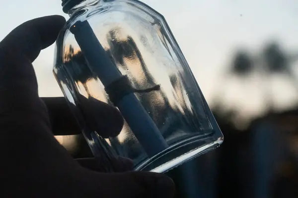 A man hand holding a bottle with a message. Message in a bottle
