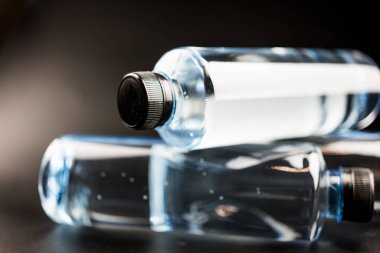 Siyah zemin üzerinde su olan şişeleri kapat