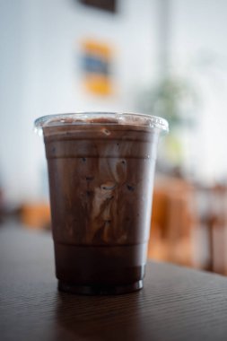 Buzlu, bir kafedeki ahşap bir masaya yerleştirilmiş, camla siyah bir moka. Kapat.