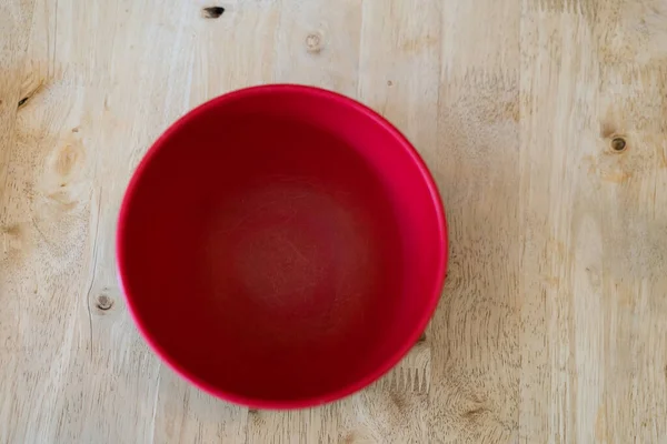 Empty plastic red bowl on wood background