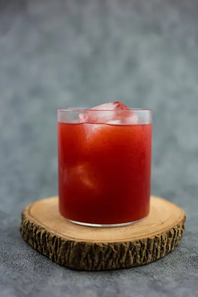 Fresh cold pressed watermelon juice with ice on a wooden coaster. Seasonal drinks. Close up