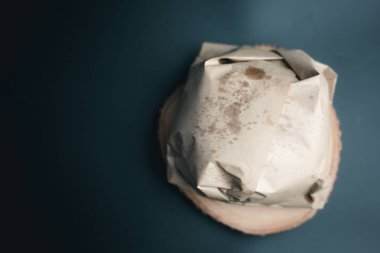 Siyah arka planda el işi kağıdına sarılı hamburger, yiyecek ambalajı.