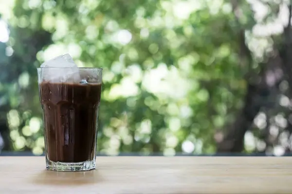 Iced Mocha coffee with homemade square ice cubes on the table and on a nature background.