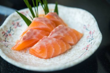 Dilimlenmiş somon balığı, Japon çiğ yemek menüsü beyaz tabakta servis edilir..