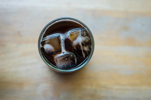 Overhead view of iced black coffee on a wood background.