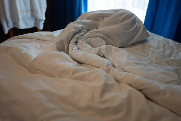 Wrinkle messy blanket and white pillow in the bedroom after waking up in the morning at hotel