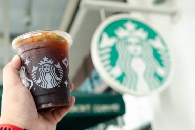 Bangkok, Tayland - 12 Aralık 2023 Starbucks 'ta Starbucks' ın logosunun yanında plastik bardakta Amerikan kahvesi bulundurmak. Starbucks dünyanın en büyük kahve evi.