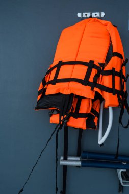 Acil durumlar için yüzme havuzuyla duvara asılmış turuncu can yelekleri..