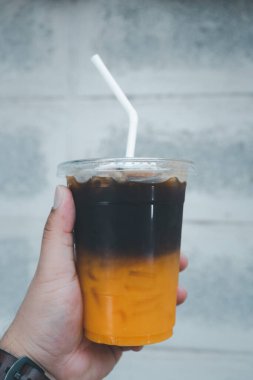 Bir bardak portakal suyu ve buzlu kahve. Arka planda çimento var..