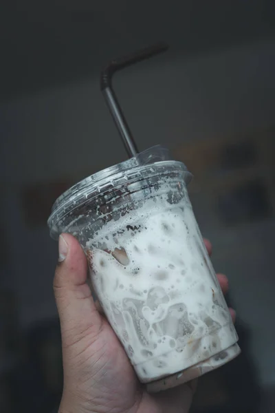 Hand holding a empty cool coffee glass after drink, show a texture of ice and milk