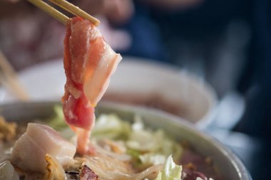 Thai barbekü büfesi elleri Tayland usulü domuz tavasında çiğ domuz eti ızgara yapmak için çubuk kullanıyorlar. Kapat.