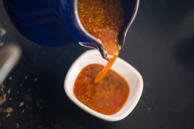 Kavanozdan susam tohumlu sukiyaki sosu dök. Tayland baharatlı sos ve doğranmış taze biber sosu.