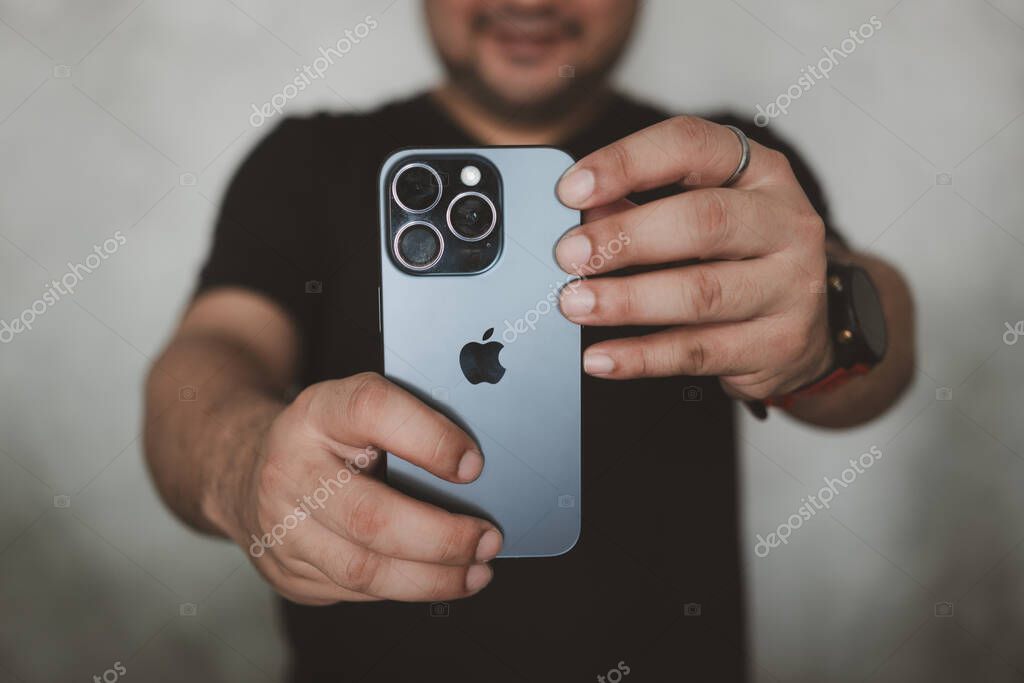 Bangkok, Thailand - December 15, 2023 : A young man taking a photo with iPhone 15 pro features, triple-lens camera setup with 5x optical zoom.