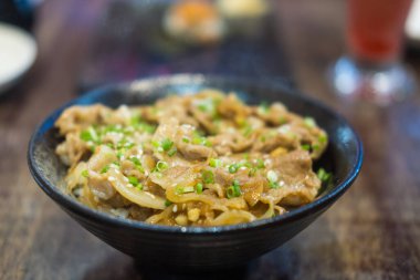 Lezzetli kızarmış domuz shabu üstü siyah kasede pilav.