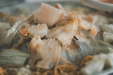 Elektrikli ocakta domuz eti ya da Mookata. Moo ka ta alüminyum bir kubbe kömürle doldurulmuş küçük bir kil ateş tenceresine konur.