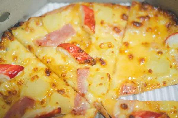 Pizza with ham and crab sticks placed on a paper box. Close up and selective focus