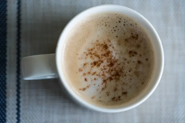 A hot cup of coffee from above in a white cup, morning drink