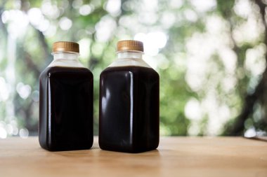 Ahşap masada plastik bir şişede iki tane Americano kahvesi.