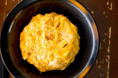 Siyah kasede pirinç üzerine kremalı omlet. Yumuşak omlet pilavı kaplar.