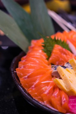 Sashimi Seti (Çiğ Somon ve Ton Balığı) dilimlenmiş ve siyah bir kasede servis edilmeye hazırdır. Popüler Japon yemekleri.