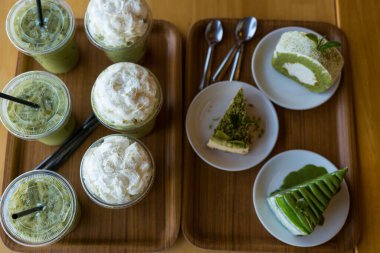 Birçok paket plastik bardak lezzetli buzlu yeşil çay veya buzlu kibrit ve bir sürü kibrit yeşil çay keki. Sağlıklı ferahlatıcı yaz içkileri konsepti.