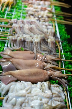 Tayland usulü çiğ kalamar. Gece pazarında ızgarada. Taze mürekkep balığına odaklan.